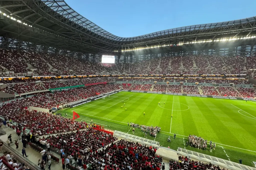 Packed football stadium in Morocco filled with fans watching a live AFCON 2025 match under stadium lights.